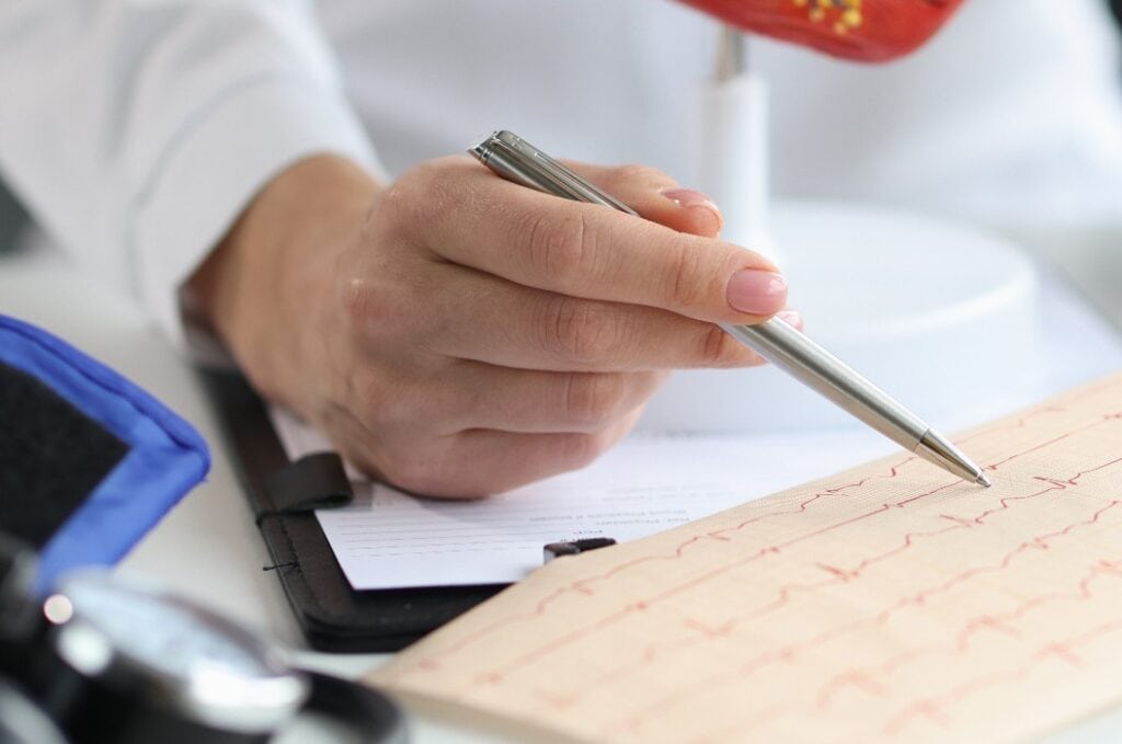 Doctor cardiologist examines electrocardiogram of patient heart in cardiology