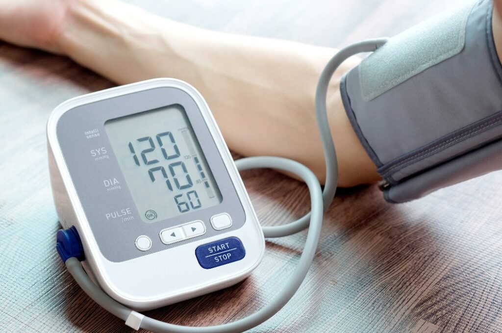 Mann überprüft Blutdruckmessgerät und Herzfrequenzmesser mit digitalem Druckmessgerät. Gesundheits- und Medizinisches Konzept.